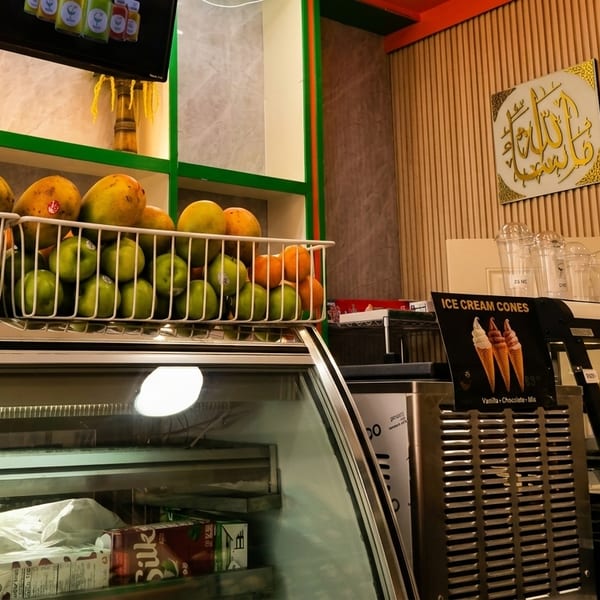 Fresh fruit baskets, a refrigerated display case, and an ice cream cone sign in a cafe.